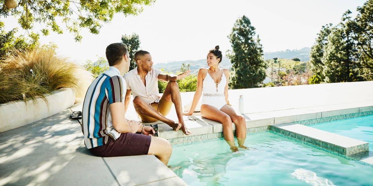 three male and one female friend relaxing by the pool at a vacation rental